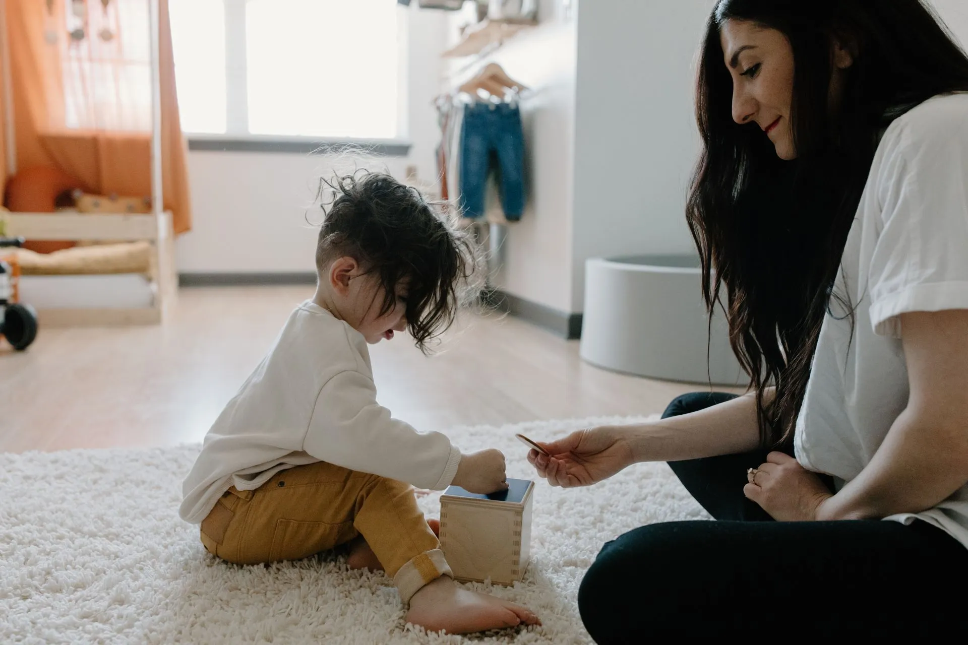 Parent and toddler playing together on the living room floor