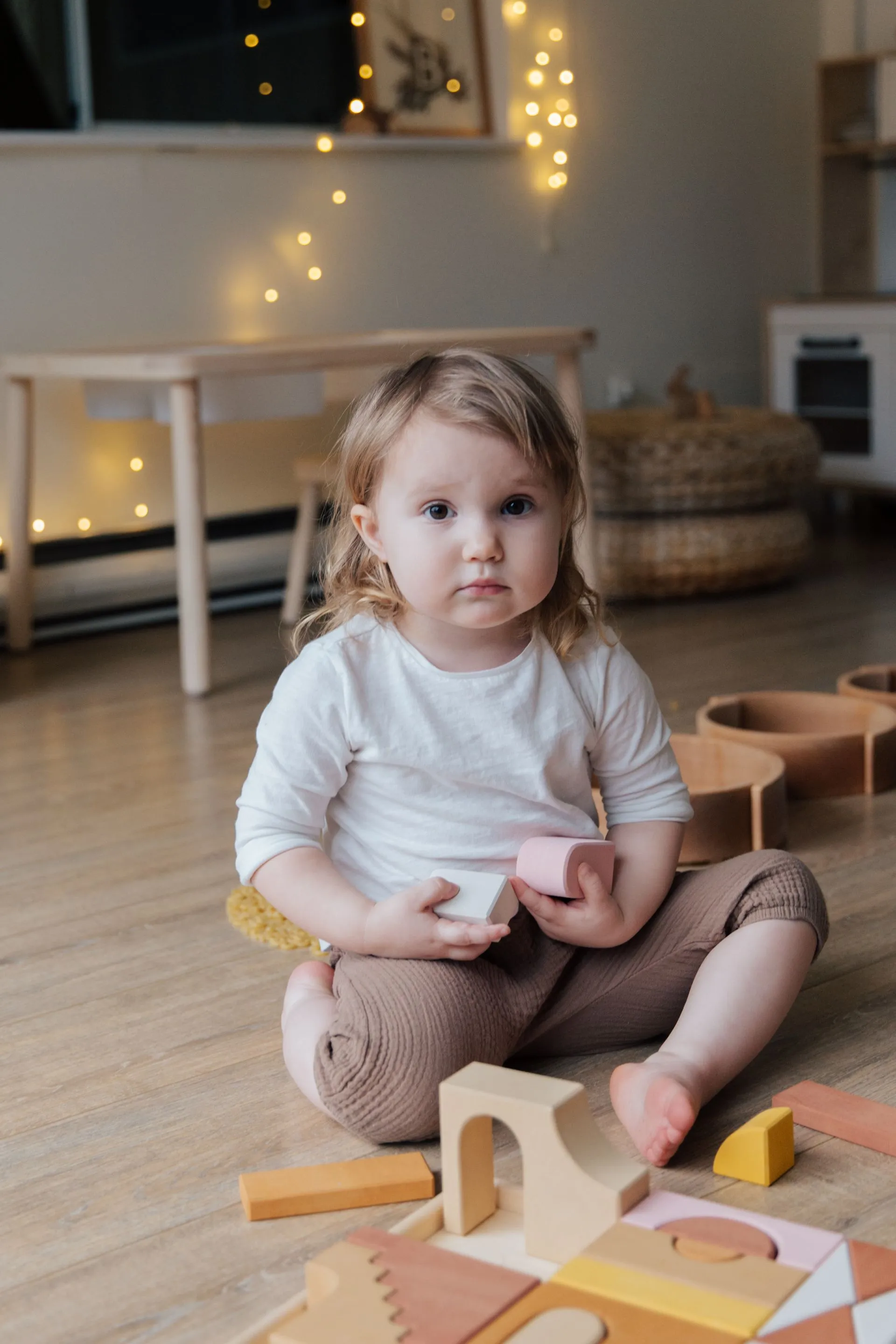 Toddler holding wooden blocks while playing on the floor at home